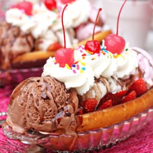 Close up of a Doughnut Ice Cream Sundae with whipped cream and cherries on top.