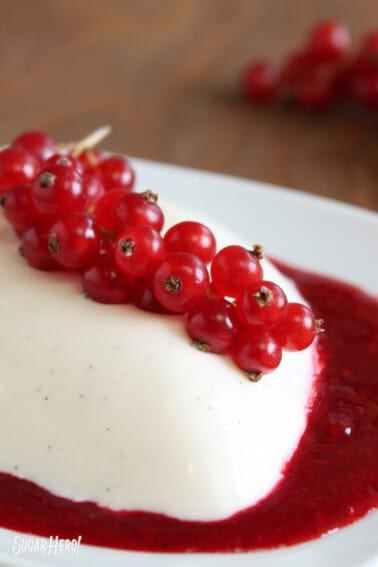 Vanilla Bean Panna Cotta in a pool of berry puree with berries on top.