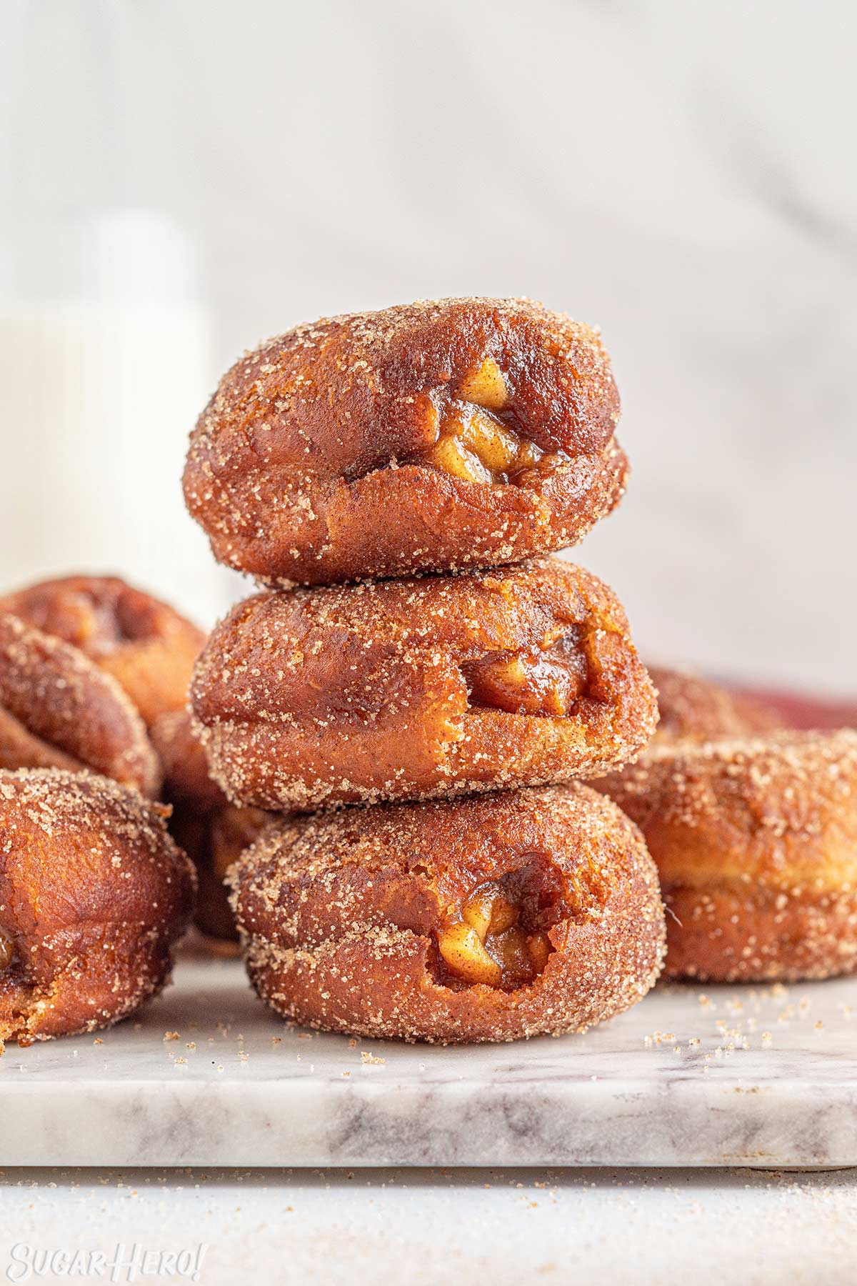 Three Apple Donuts stacked on top of each other on a marble surface.