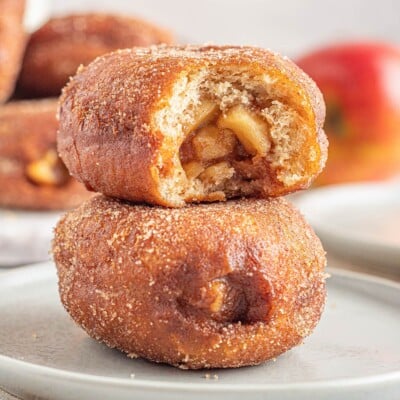 Two Apple Donuts stacked on top of each other, with a bite taken out of the top donut.
