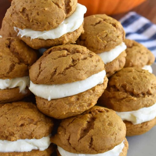 Stack of Pumpkin Whoopie Pies with a real pumpkin in the background.