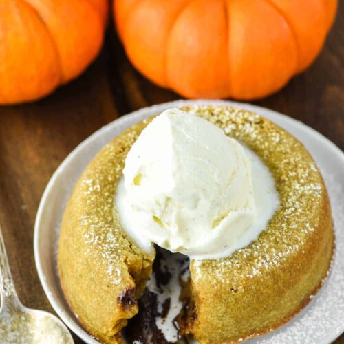 Pumpkin Lava Cake on a small white plate, cut open to show chocolate filling oozing out.