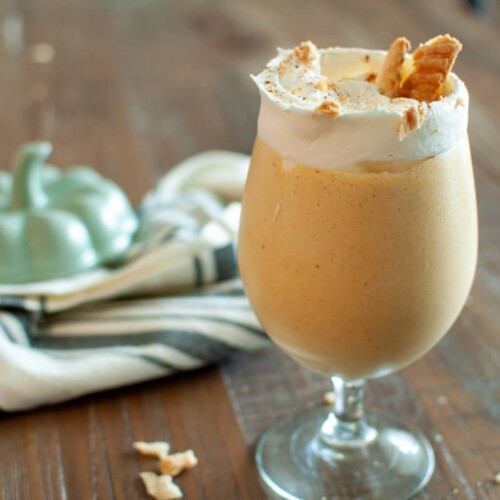 Pumpkin Pie Milkshake in a glass goblet with whipped cream and pie crust pieces on top.
