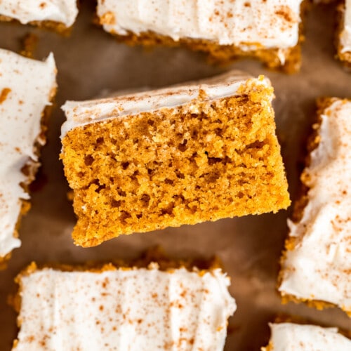 Squares of Pumpkin Sheet Cake with a layer of cinnamon-dusted cream cheese frosting on top.
