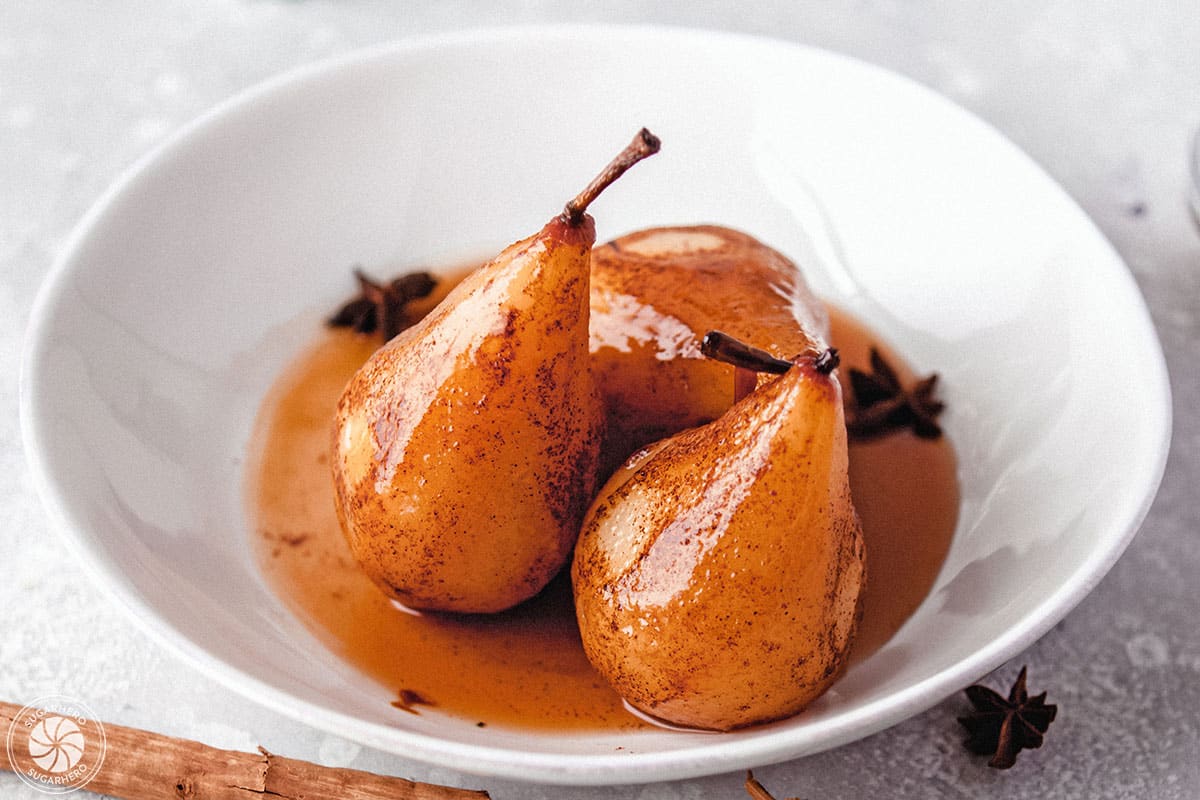 3 Poached Pears in a white bowl with their juices.