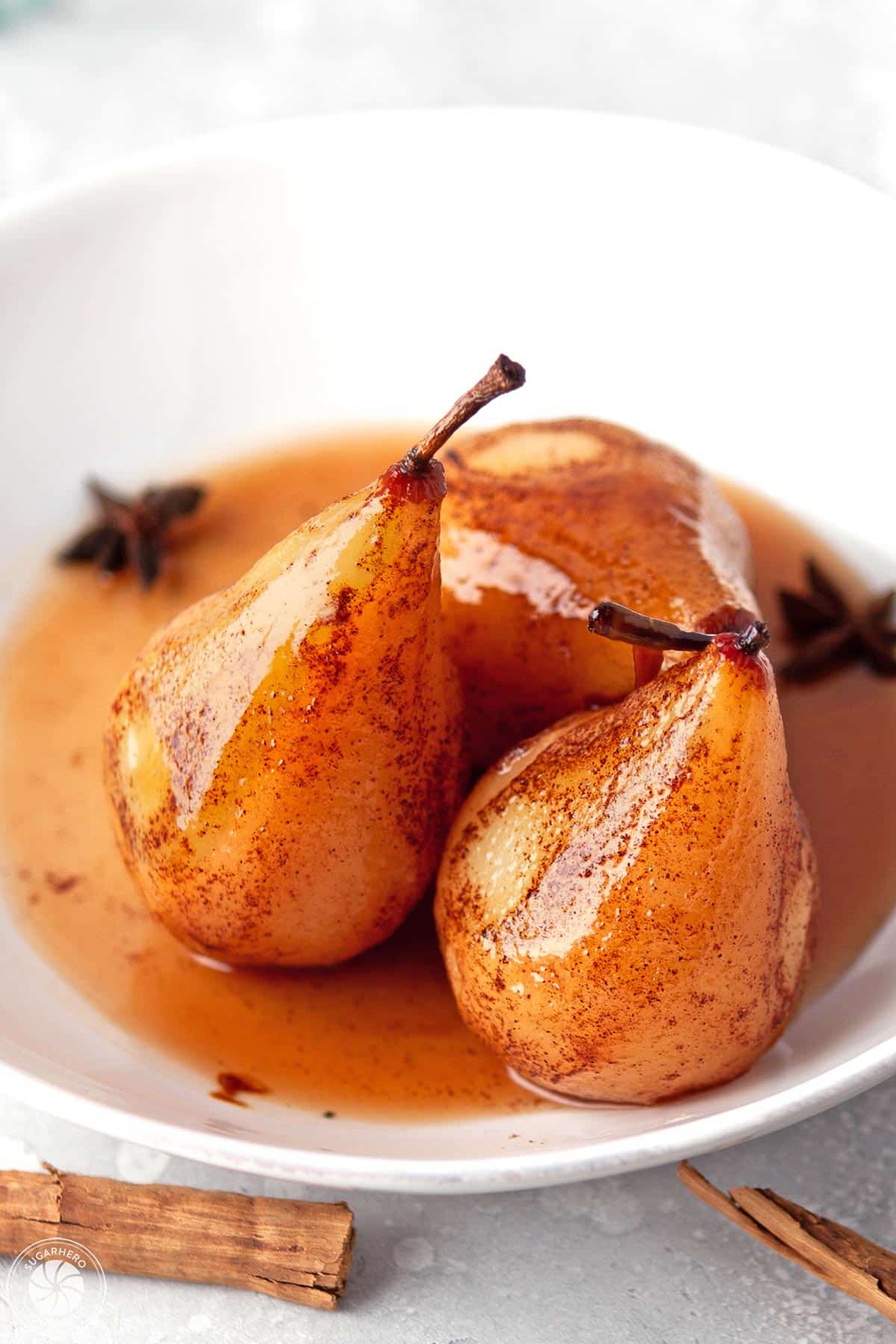 3 Poached Pears in their juices in a white bowl.