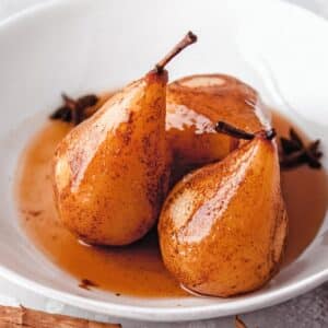 3 Poached Pears in their juices in a white bowl.