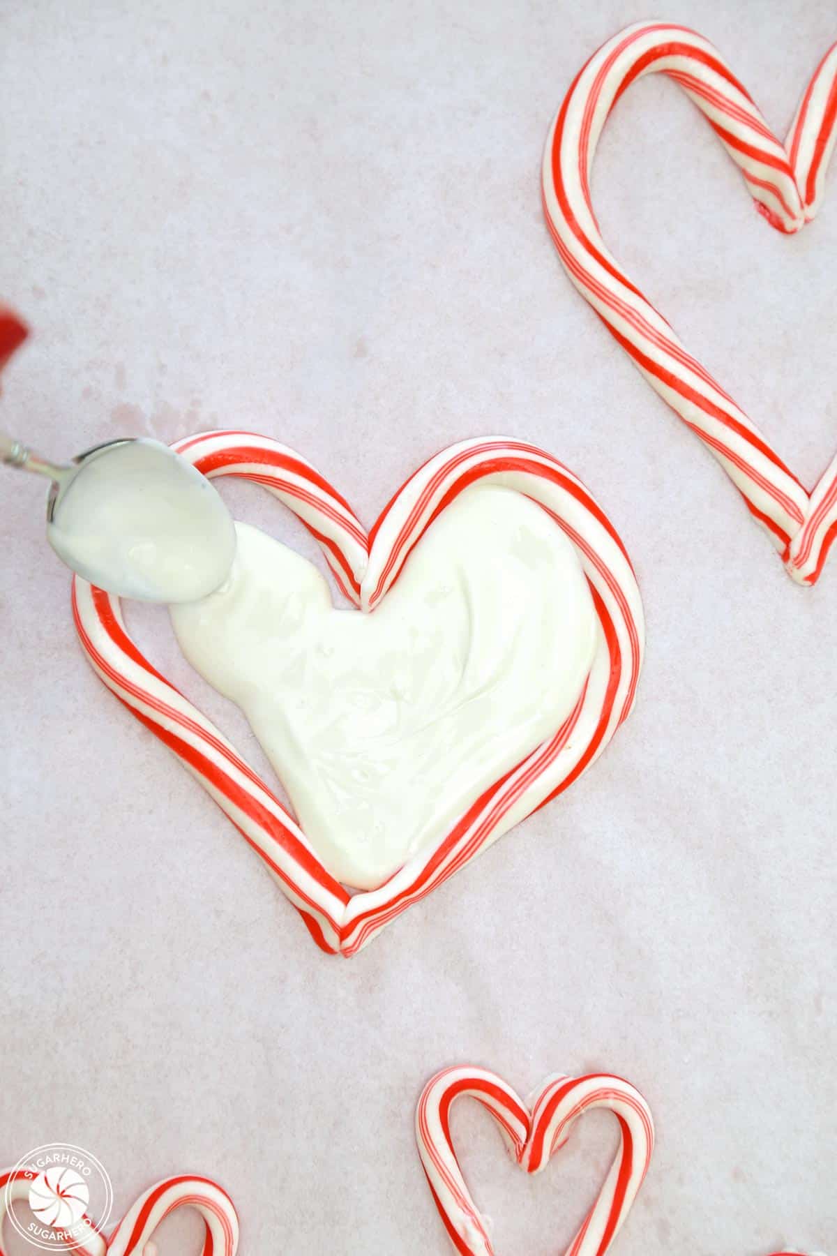 Spreading white chocolate on the inside of a heart-shaped candy cane.