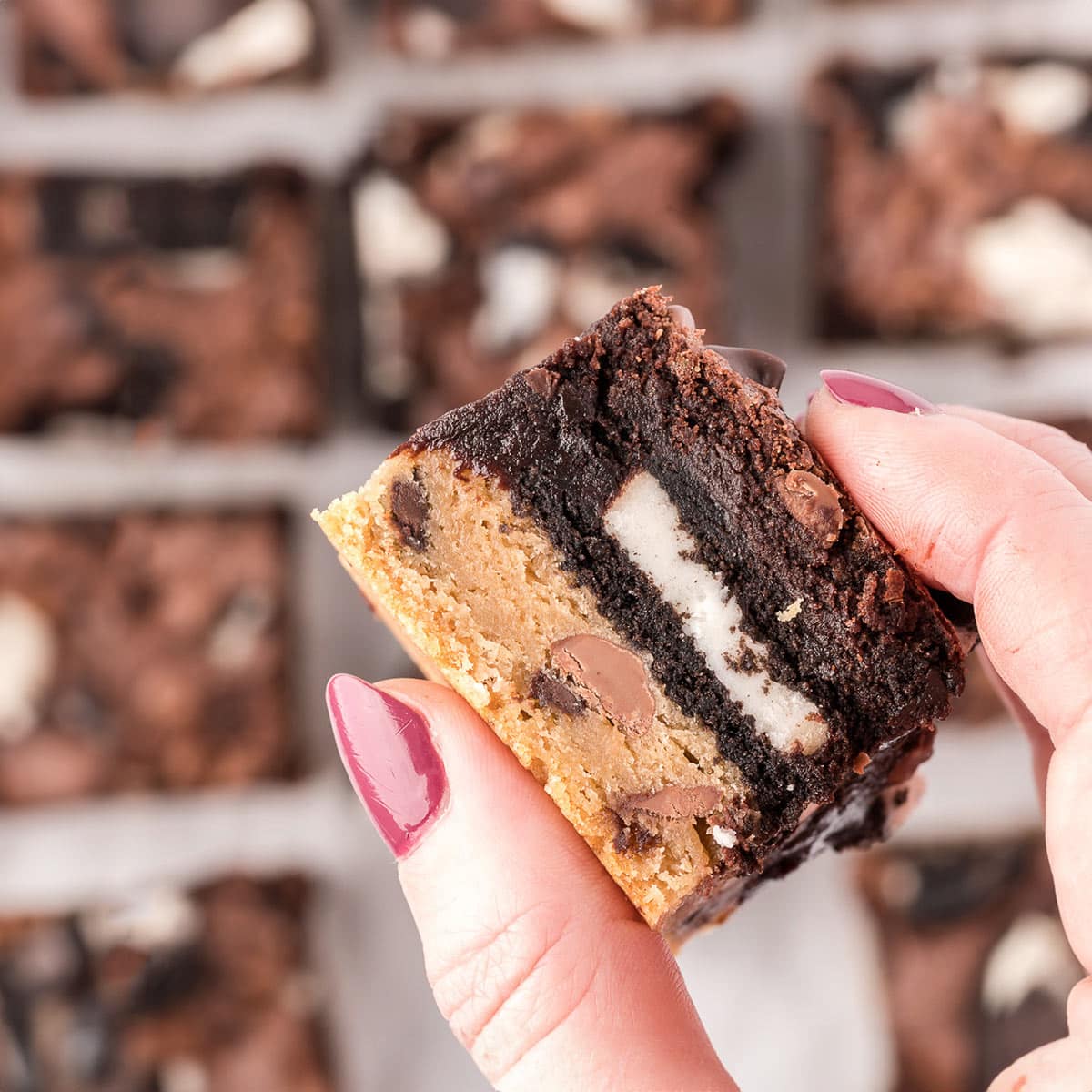 Hand with pink nails holding up an Oreo Brookie cookie bar.