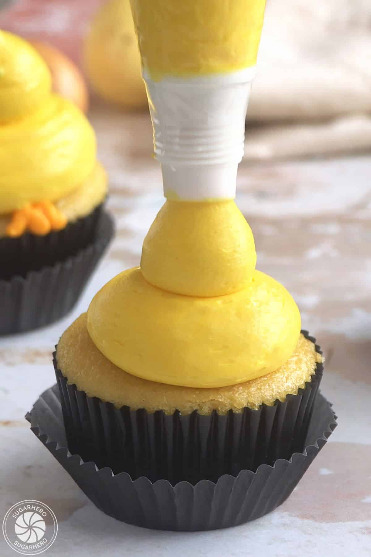 Adding a second buttercream dollop on top of a cupcake to make baby chick cupcakes.