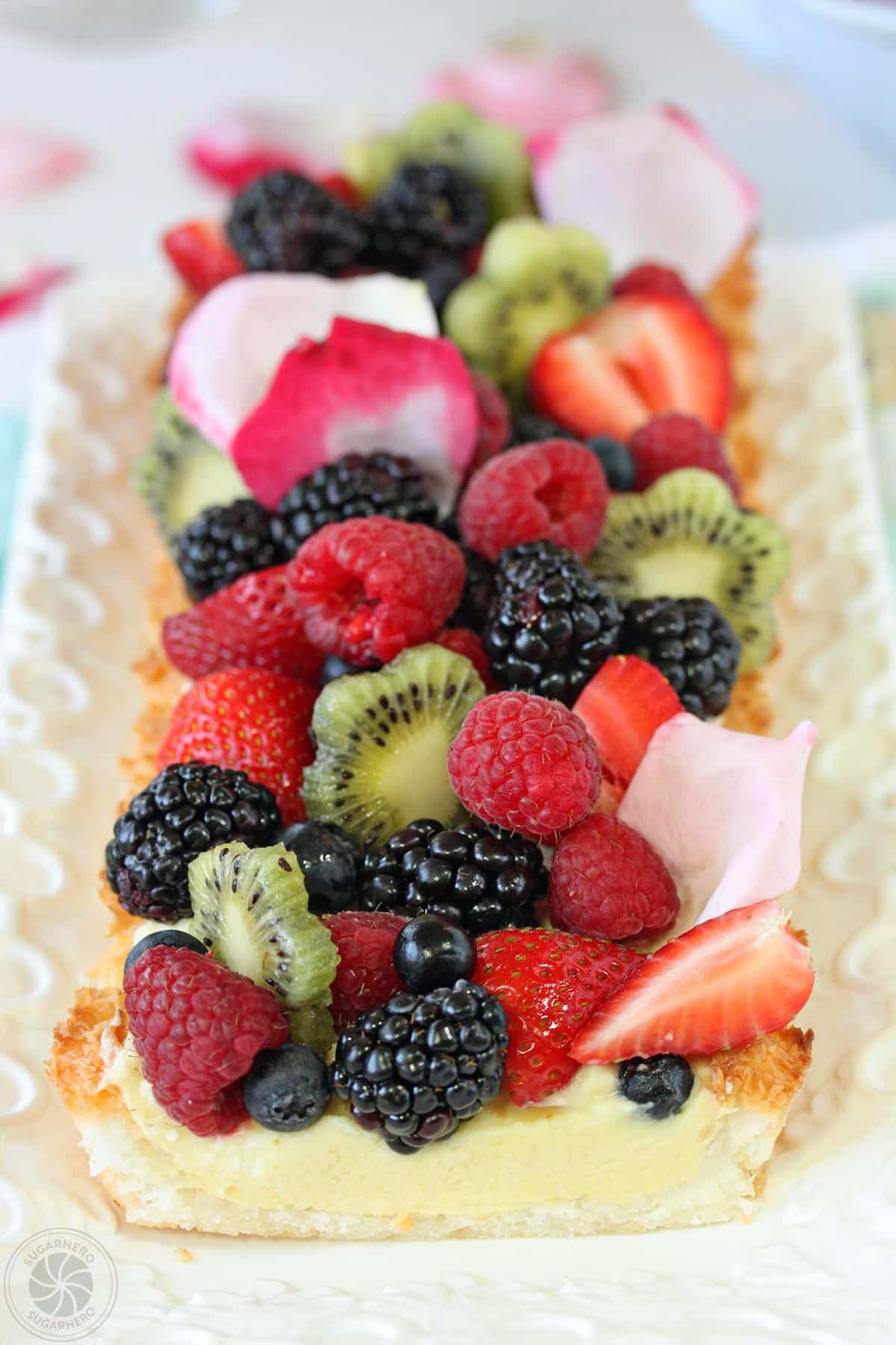 A Coconut Macaroon Tart on a white rectangular dish with a slice cut off the end.