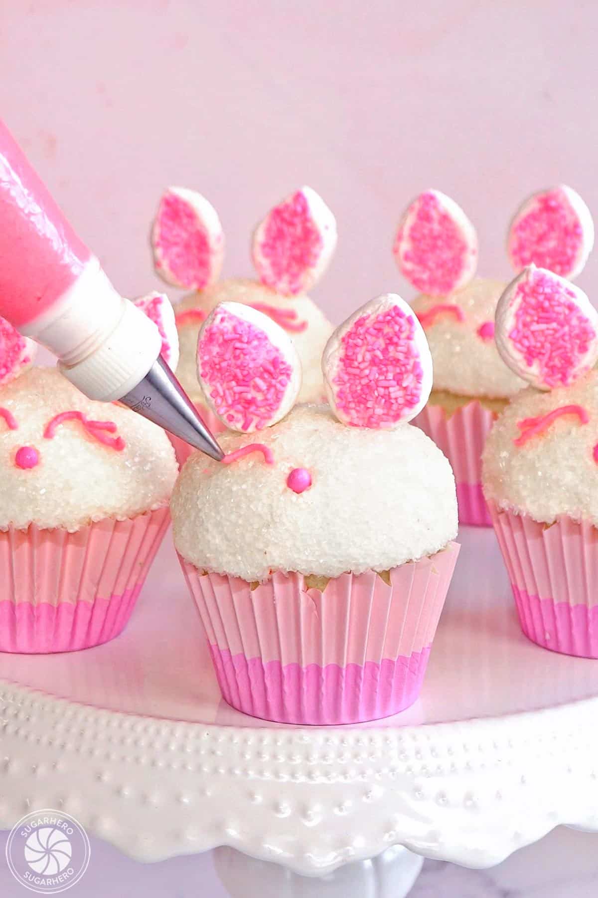 Piping pink buttercream eyes onto an Easter Bunny Cupcake.