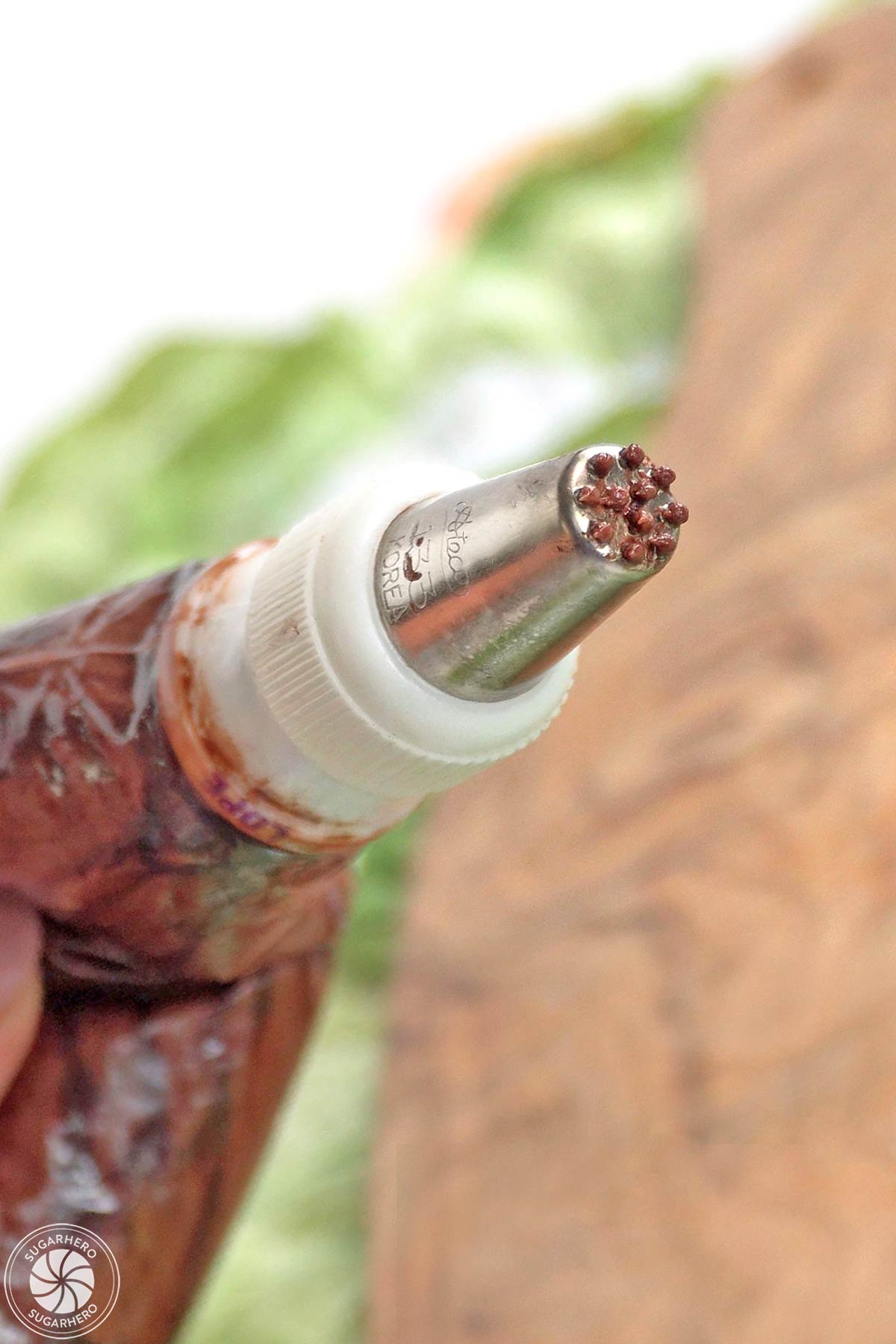 Close-up of a piping bag filled with chocolate buttercream and fitted with a grass piping tip.