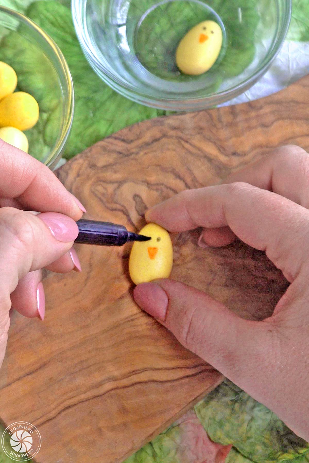 Using edible markers to draw chick faces on candy eggs.