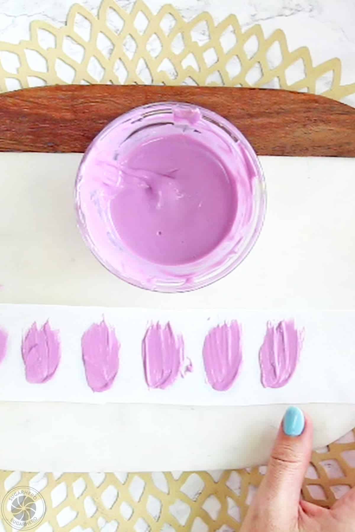 Brushing purple candy melts on a strip of parchment paper.