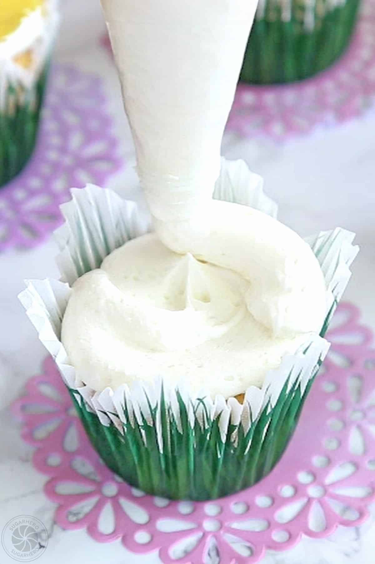 piping white buttercream on cupcakes.