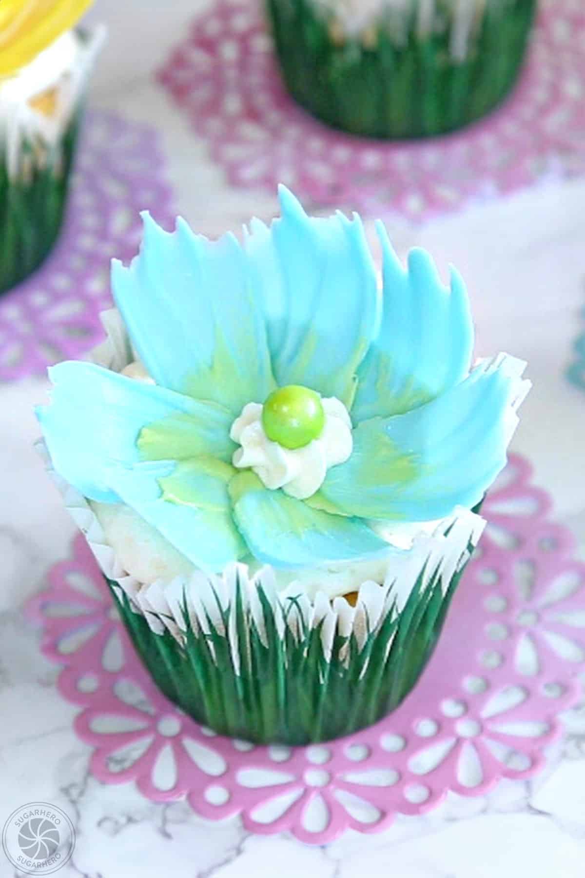 A cupcake topped with a blue candy melt flower.