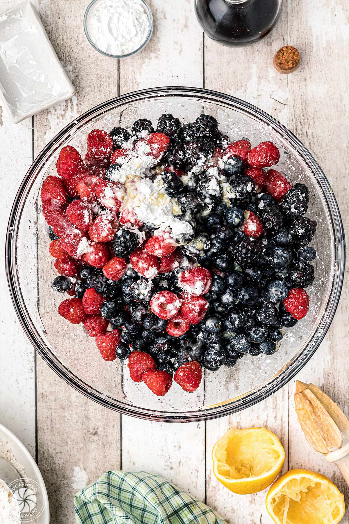 Mixed berries in a mixing bowl covered with sugar, cornstarch, vanilla and lemon juice.