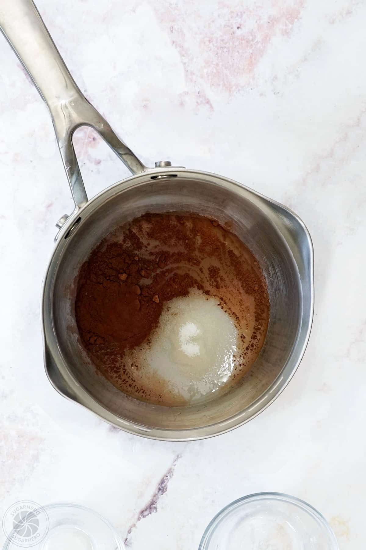 A small saucepan filled with water, granulated sugar, unsweetened cocoa powder, and salt.