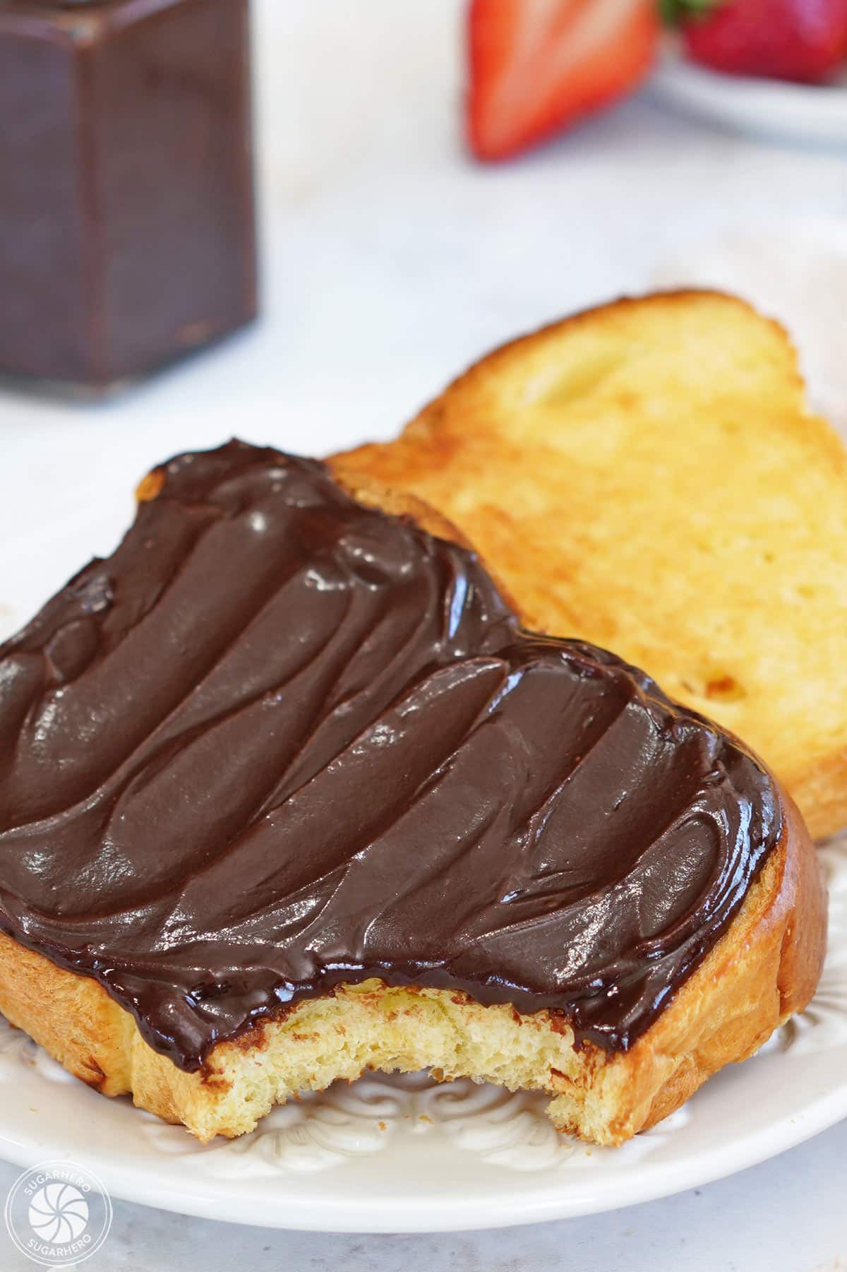 A slice of toast covered with chocolate spread, with a bite taken out of the corner.