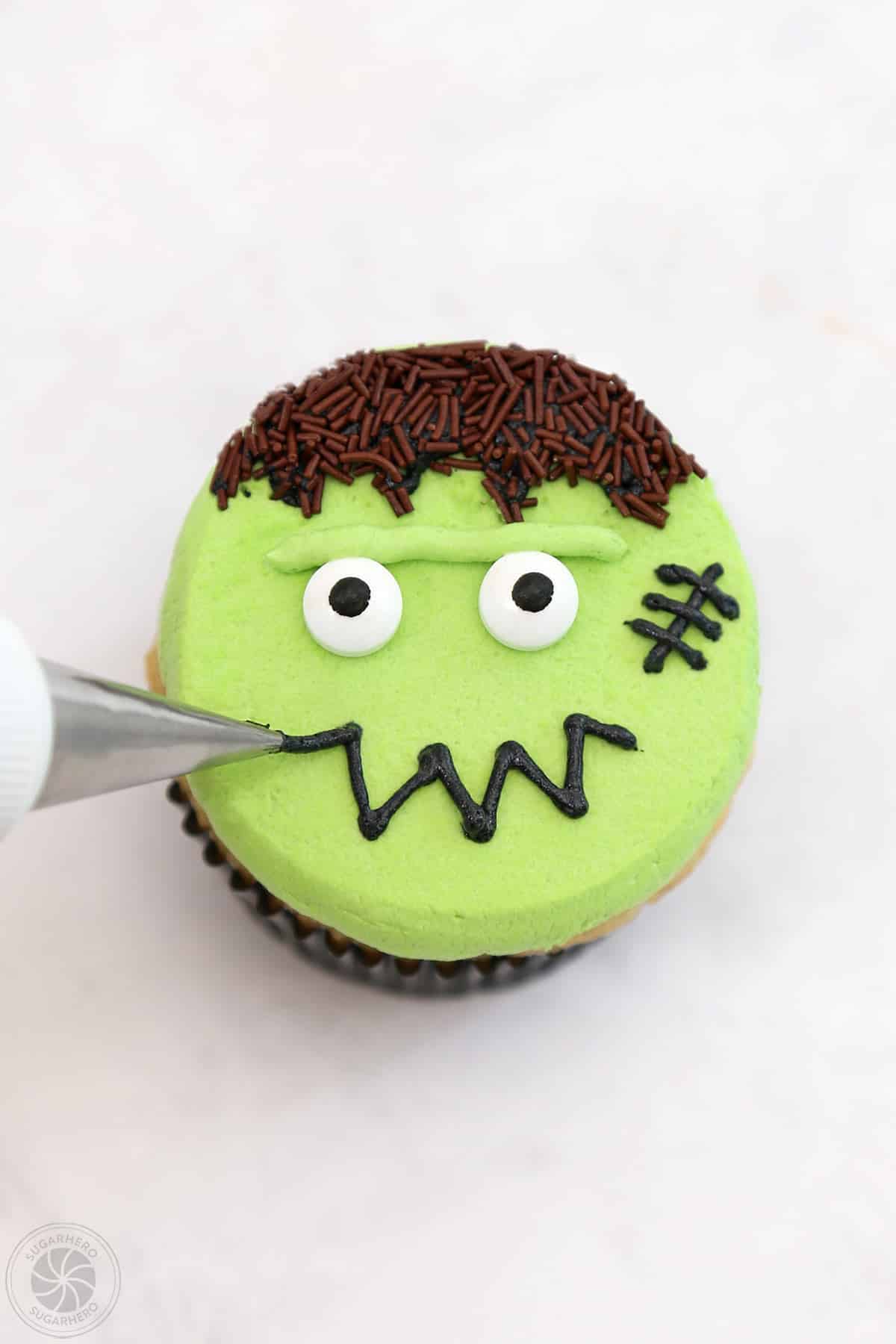A Frankenstein Cupcake with a black piped mouth and scar.