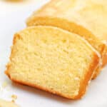 Slice of glazed lemon bread leaning up against the rest of the loaf.