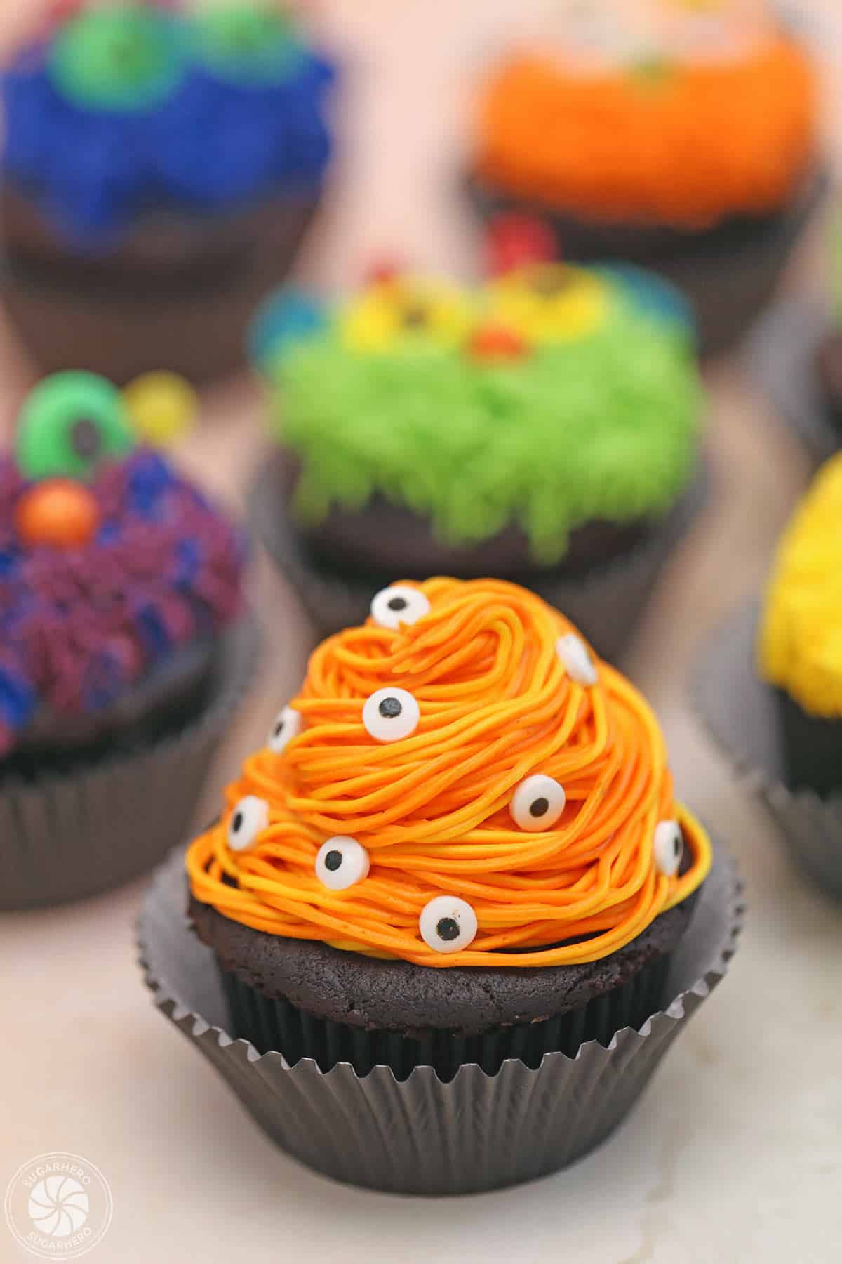 Close up of an orange monster cupcake with lots of eyeballs.