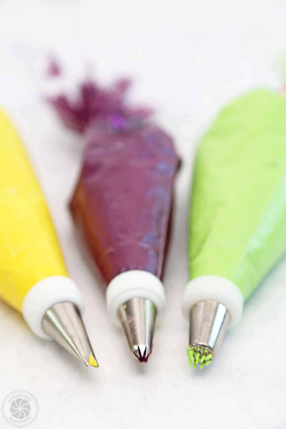 Three piping bags fitted with a leaft tip, star tip and grass tip.