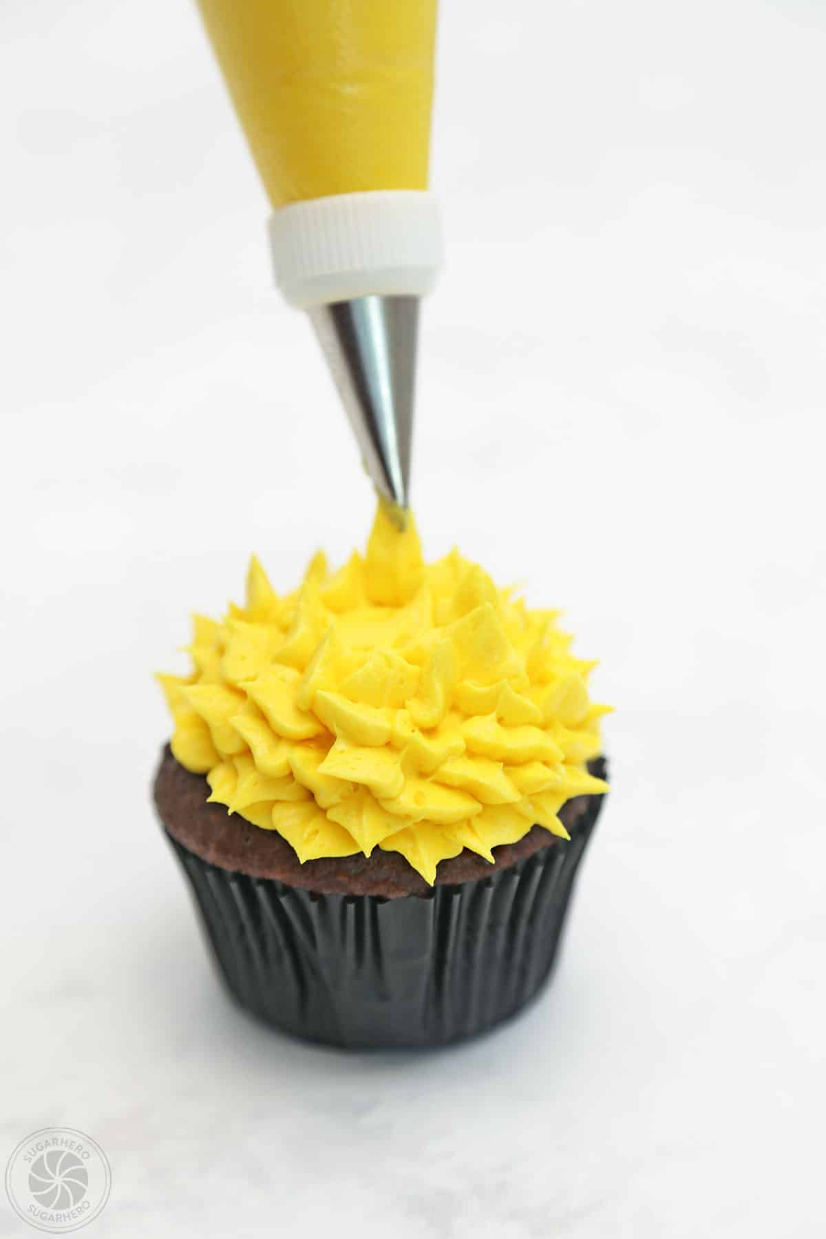 Using a leaf tip to pipe yellow fur on a monster cupcake.