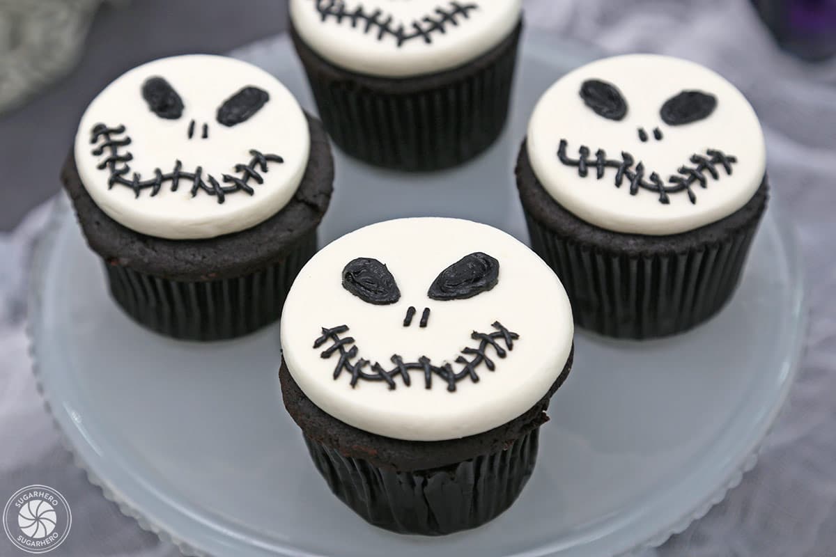 Close up of three Skull Cupcakes on a frosted glass cake plate.