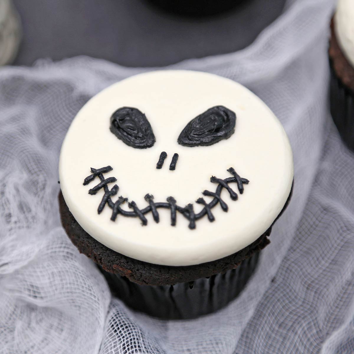Close up of a Skull Cupcake on white material.