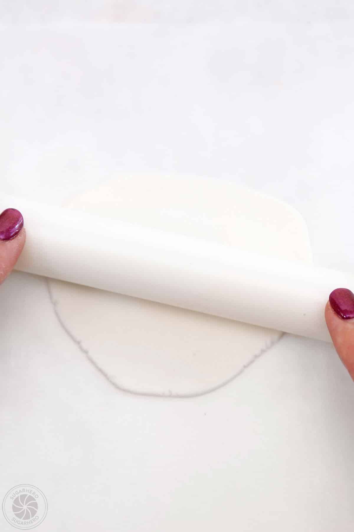 Hand rolling out white fondant.