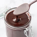 Spoon being lifted from a jar of Hot Fudge Sauce.