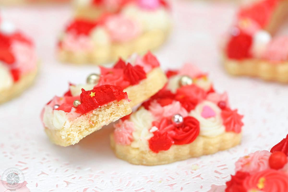 Close-up of a frosted sugar cookie with a bite taken out of it.