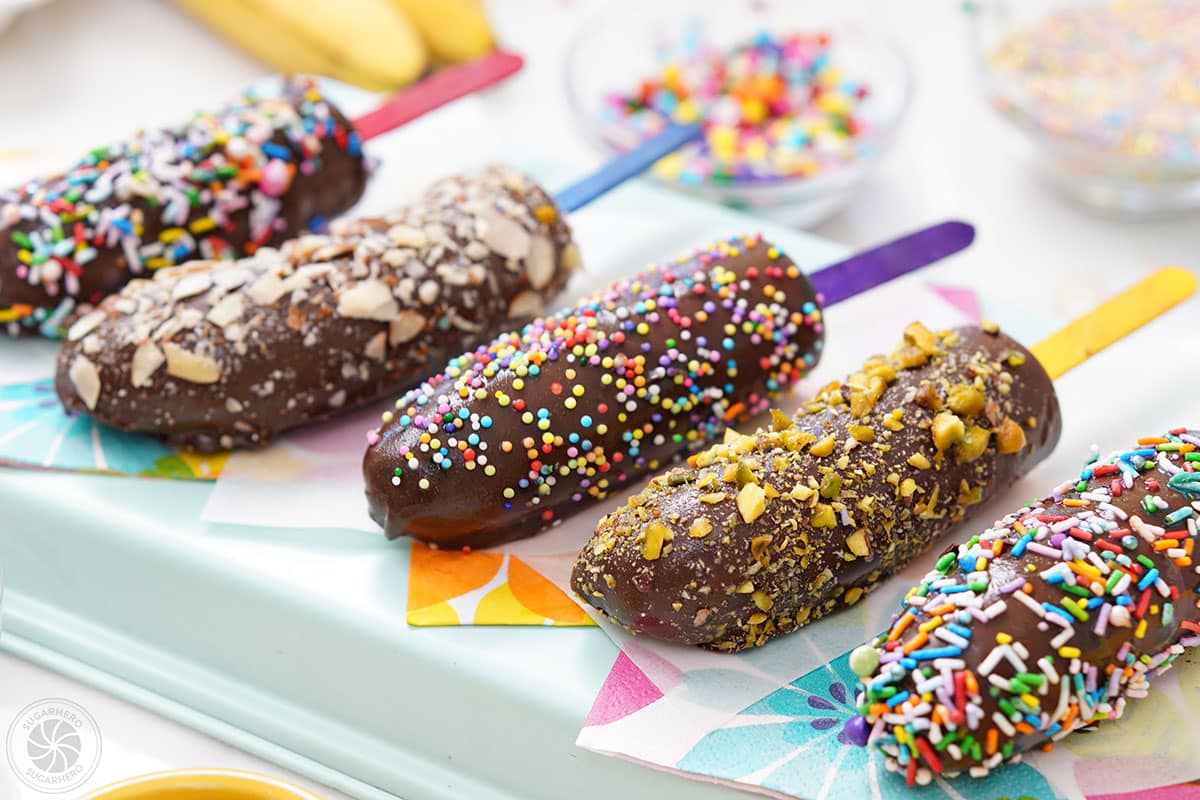 Five chocolate-dipped frozen bananas in a row.