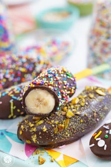 Two chocolate-dipped bananas stacked one on top of the other with the top banana cut to show the inside.