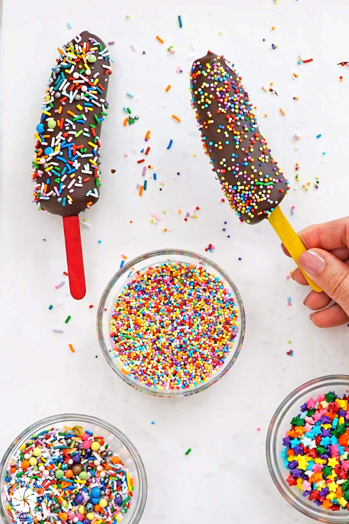 Hand holding up a freshly decorated chocolate banana.