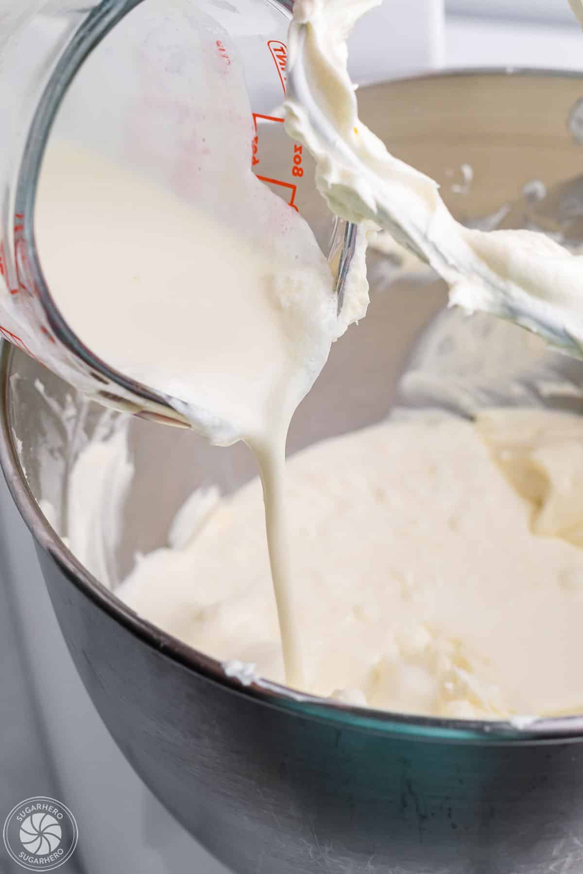 Adding cream to cheesecake filling mixture.