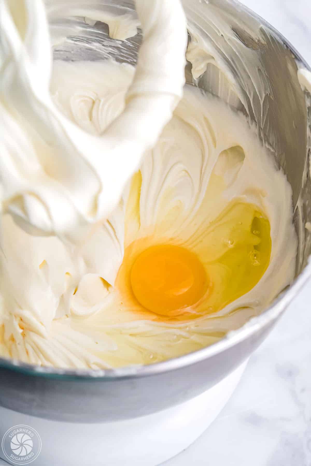 Adding eggs to cheesecake filling mixture.
