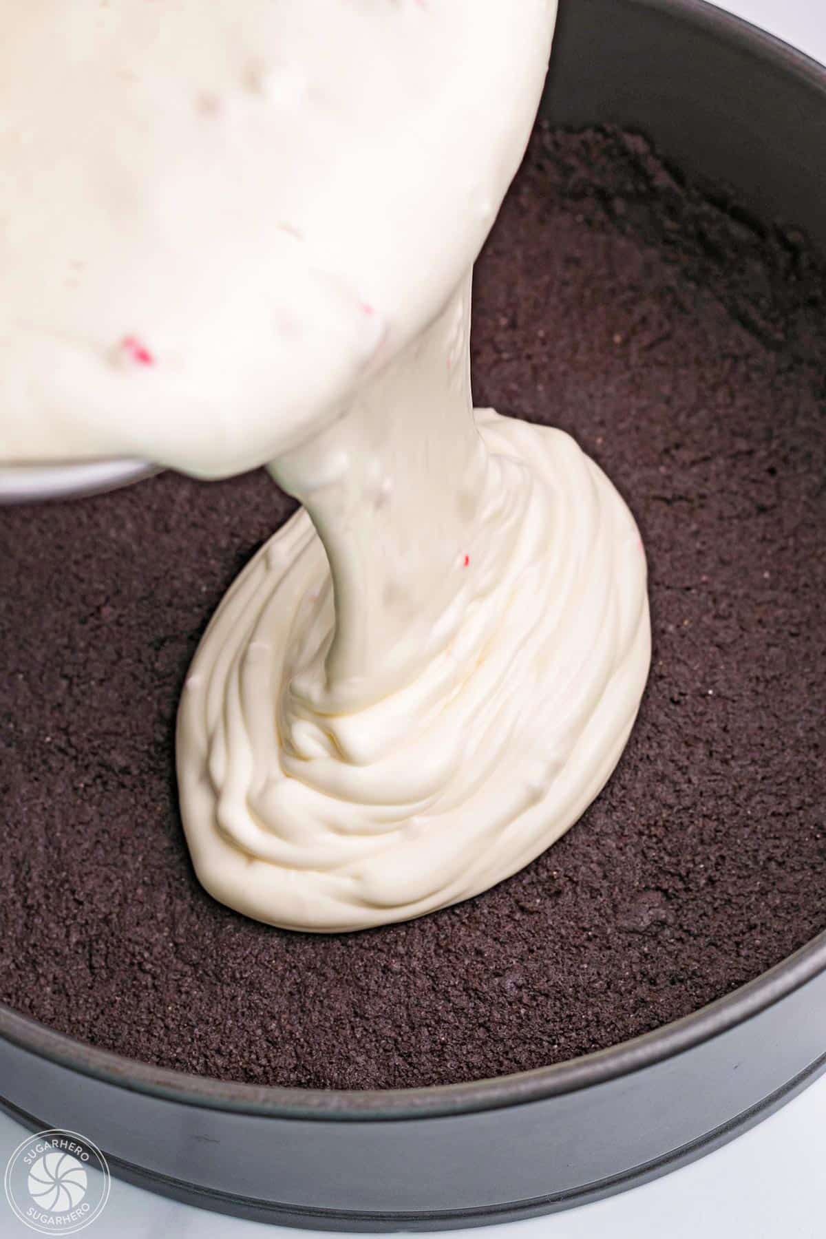 Pouring candy cane cheesecake filling into a springform pan.