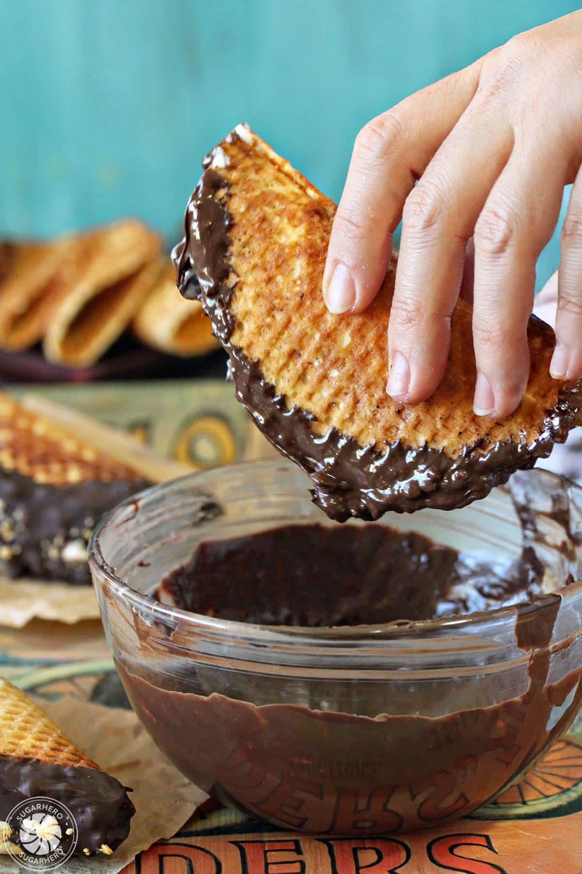 Hand dipping a homemade choco taco into a bowl of chocolate.