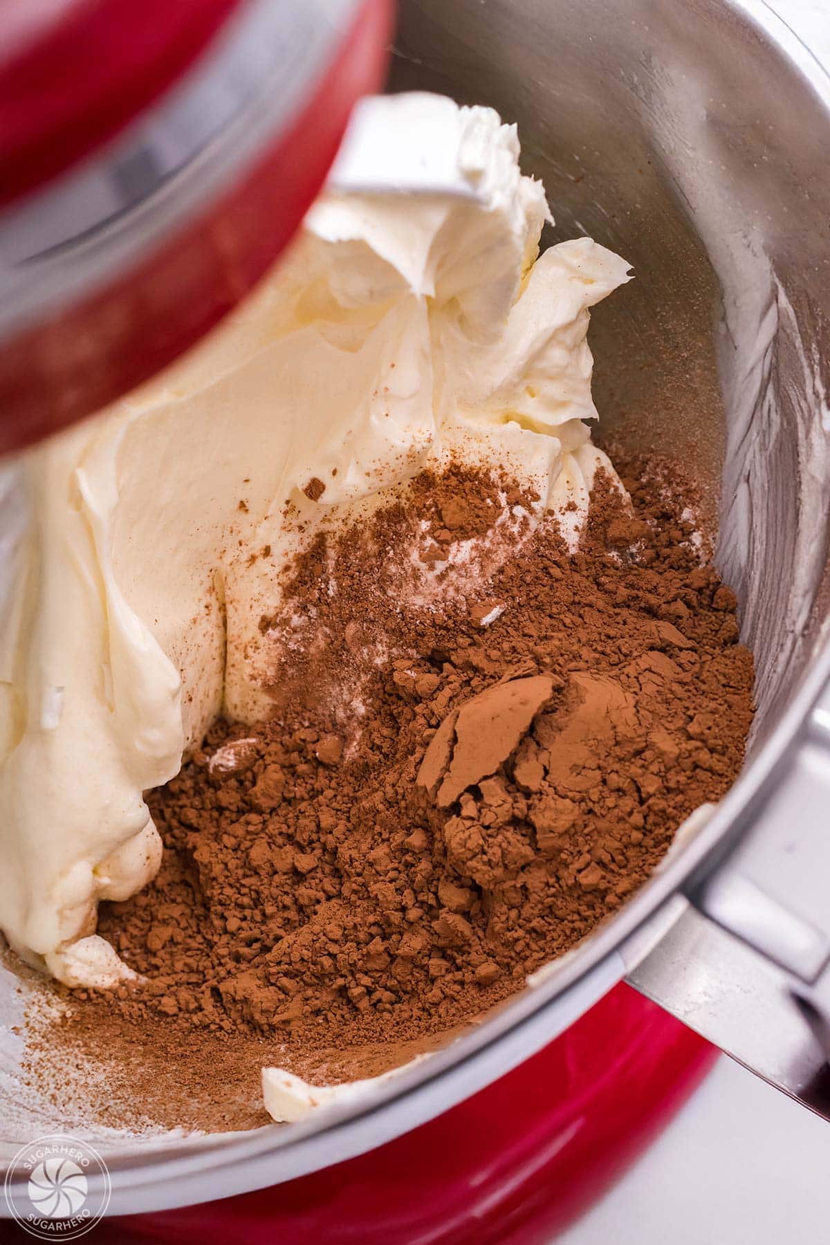 Cocoa powder added to cheesecake filling in a red mixer.