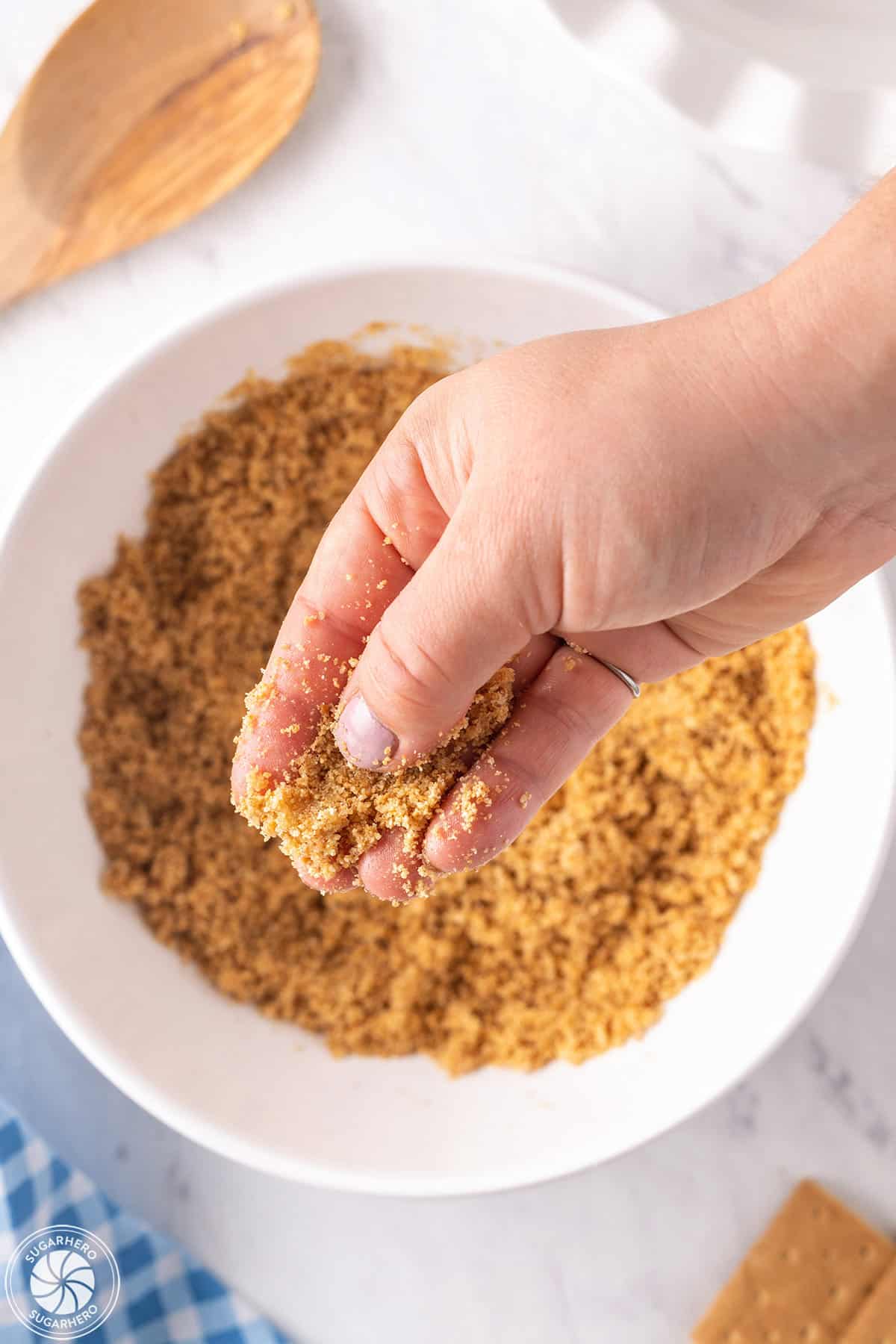 Hand holding up graham cracker crust mixture.