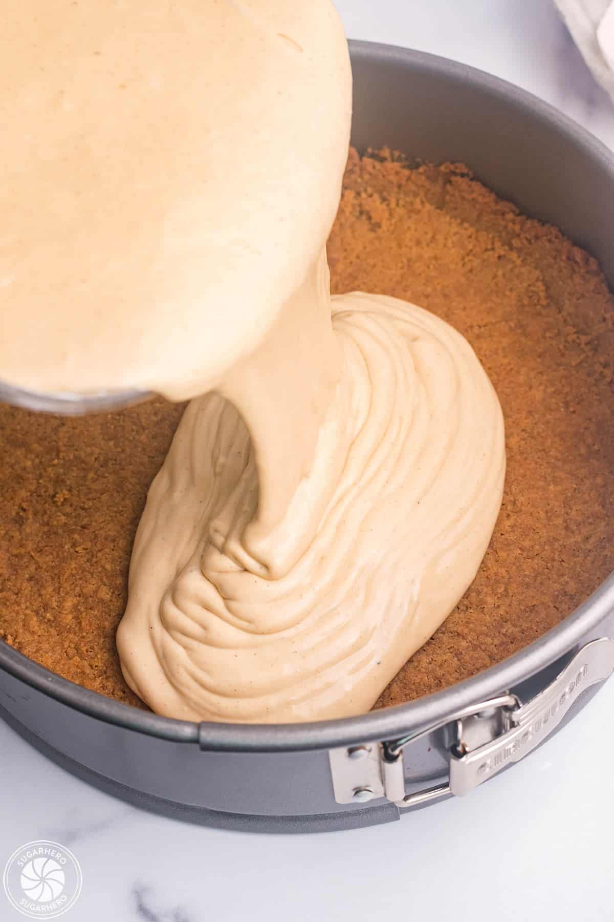 Pouring gingerbread cheesecake filling into a pan.
