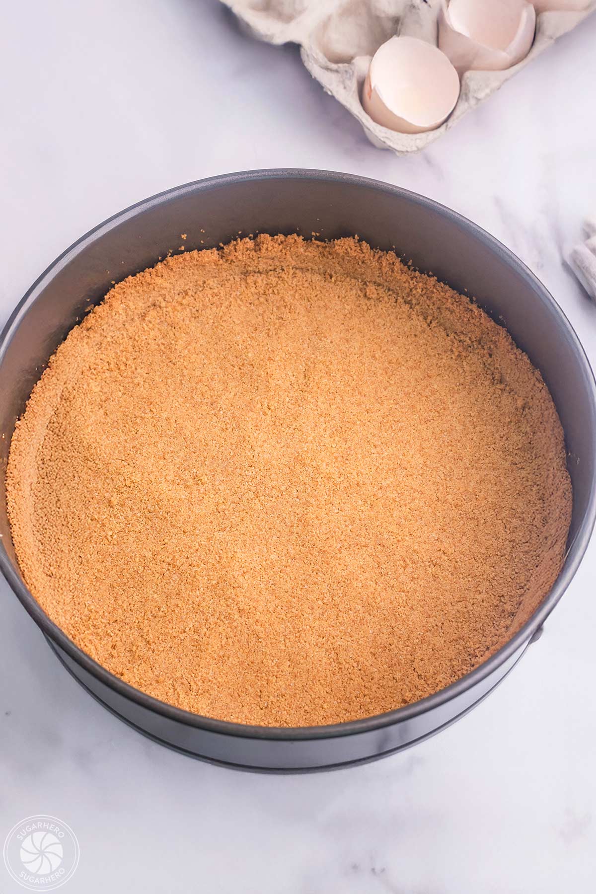 A springform pan filled with graham cracker crust.