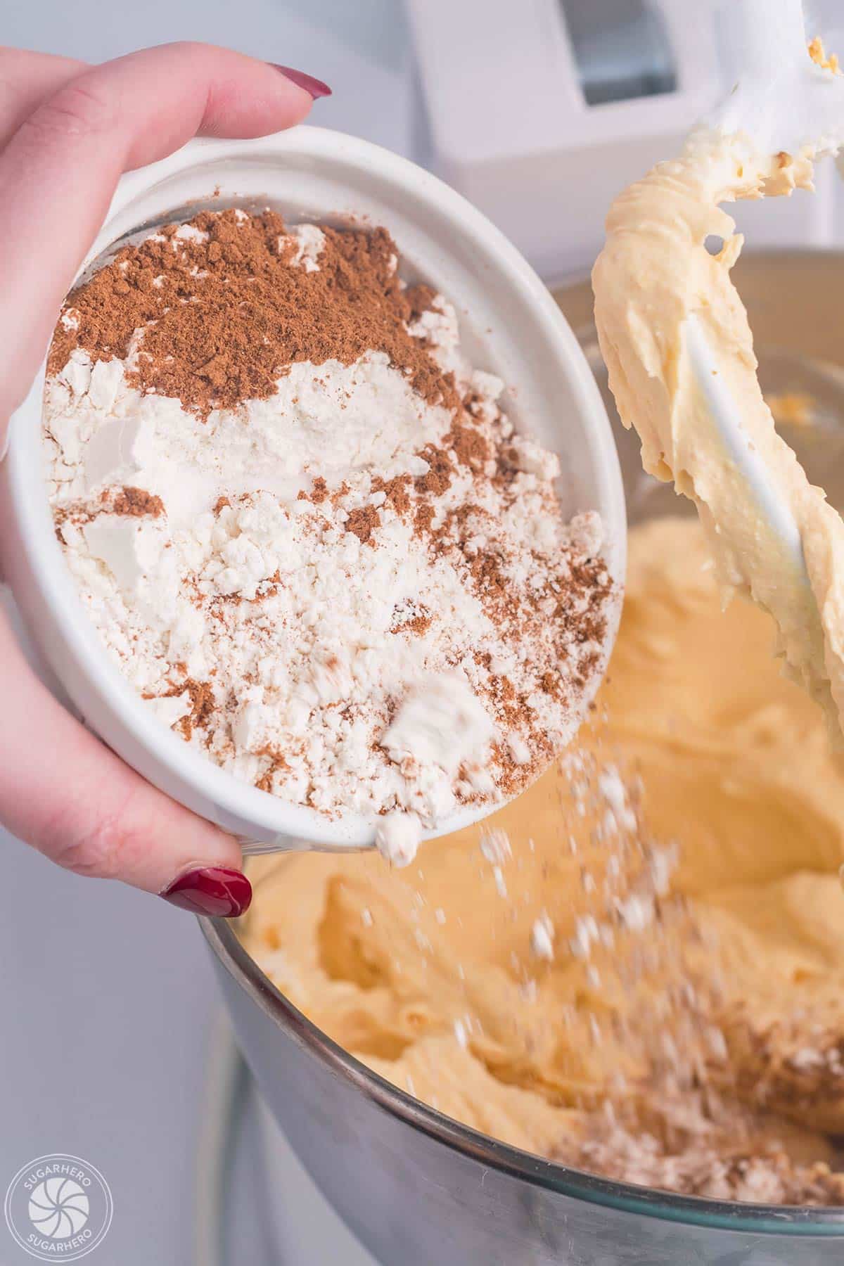 Adding flour and cinnamon to pumpkin spice cheesecake filling.