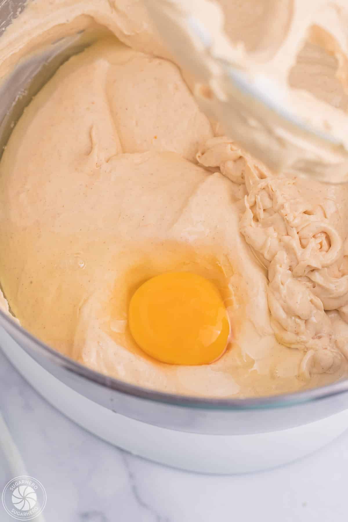 Adding an egg to pumpkin spice cheesecake filling.