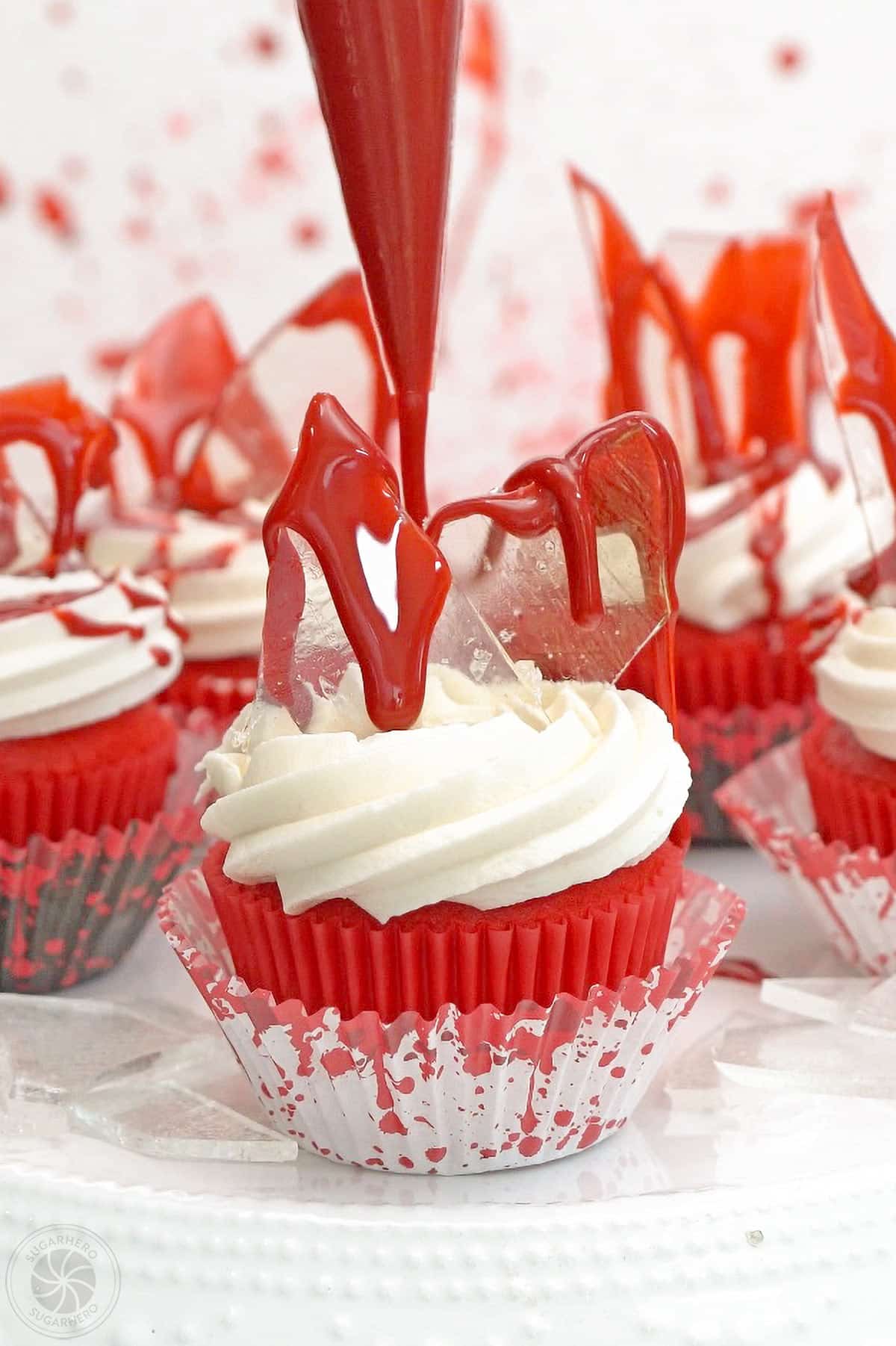 Edible blood being piped onto a bloody glass cupcake.