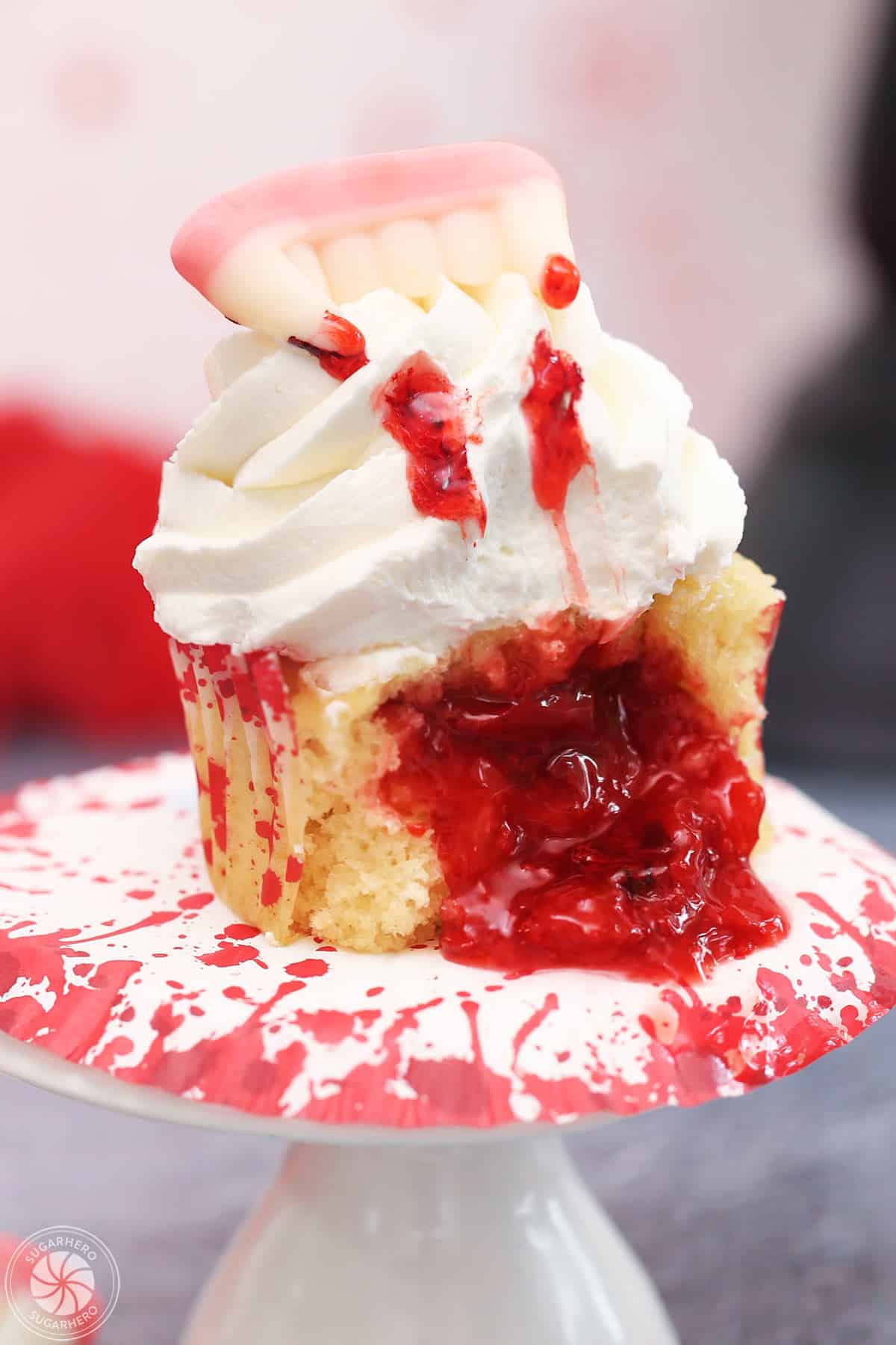 Close up of a vampire bite cupcake that's been cut to show oozing cherry filling.