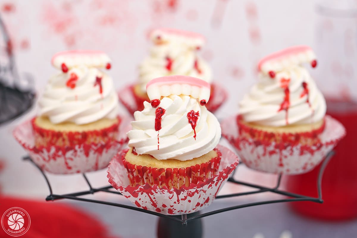Four vampire bite cupcakes on a black web cake stand.